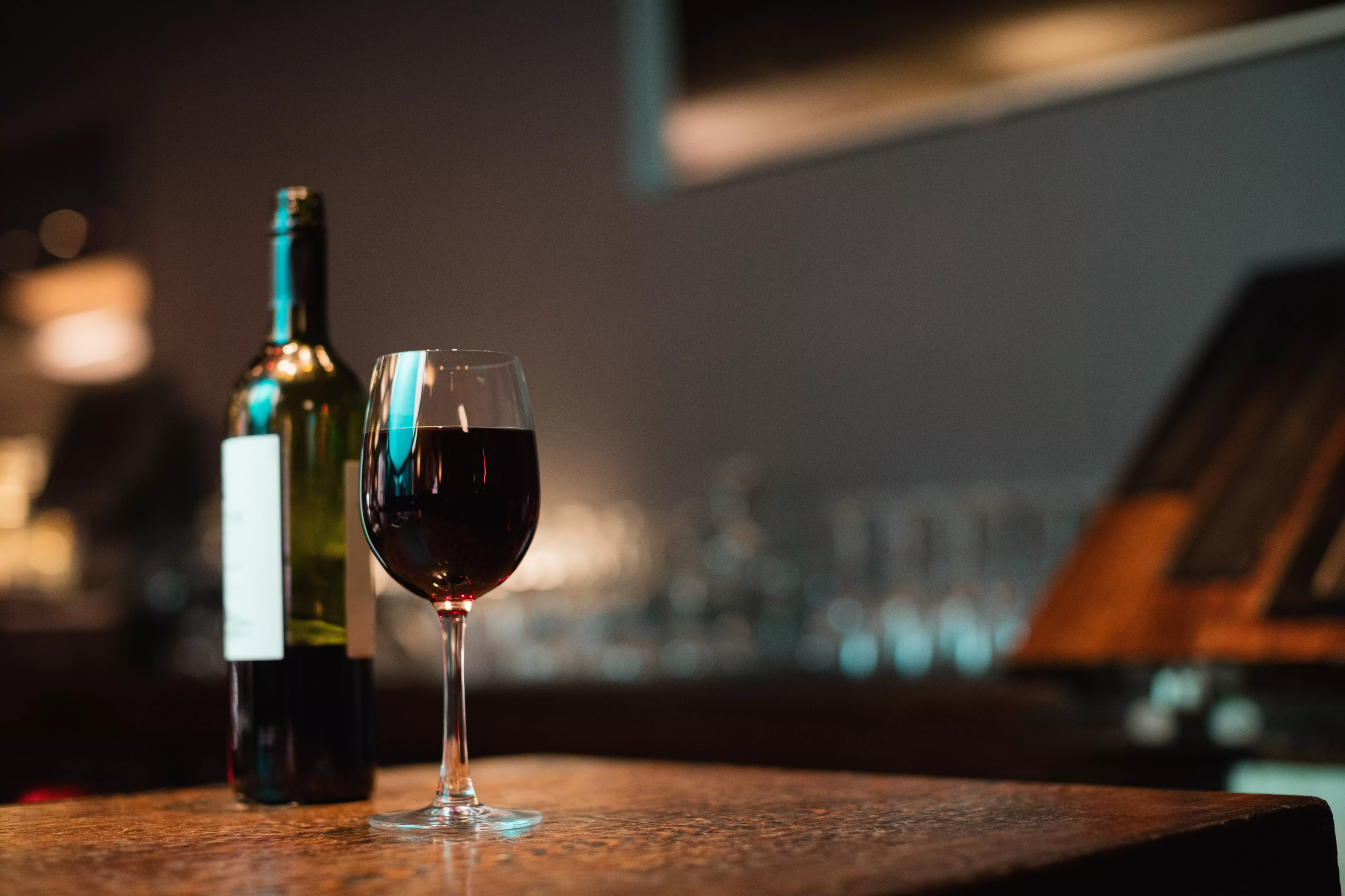 Glass of red wine and bottle on bar counter